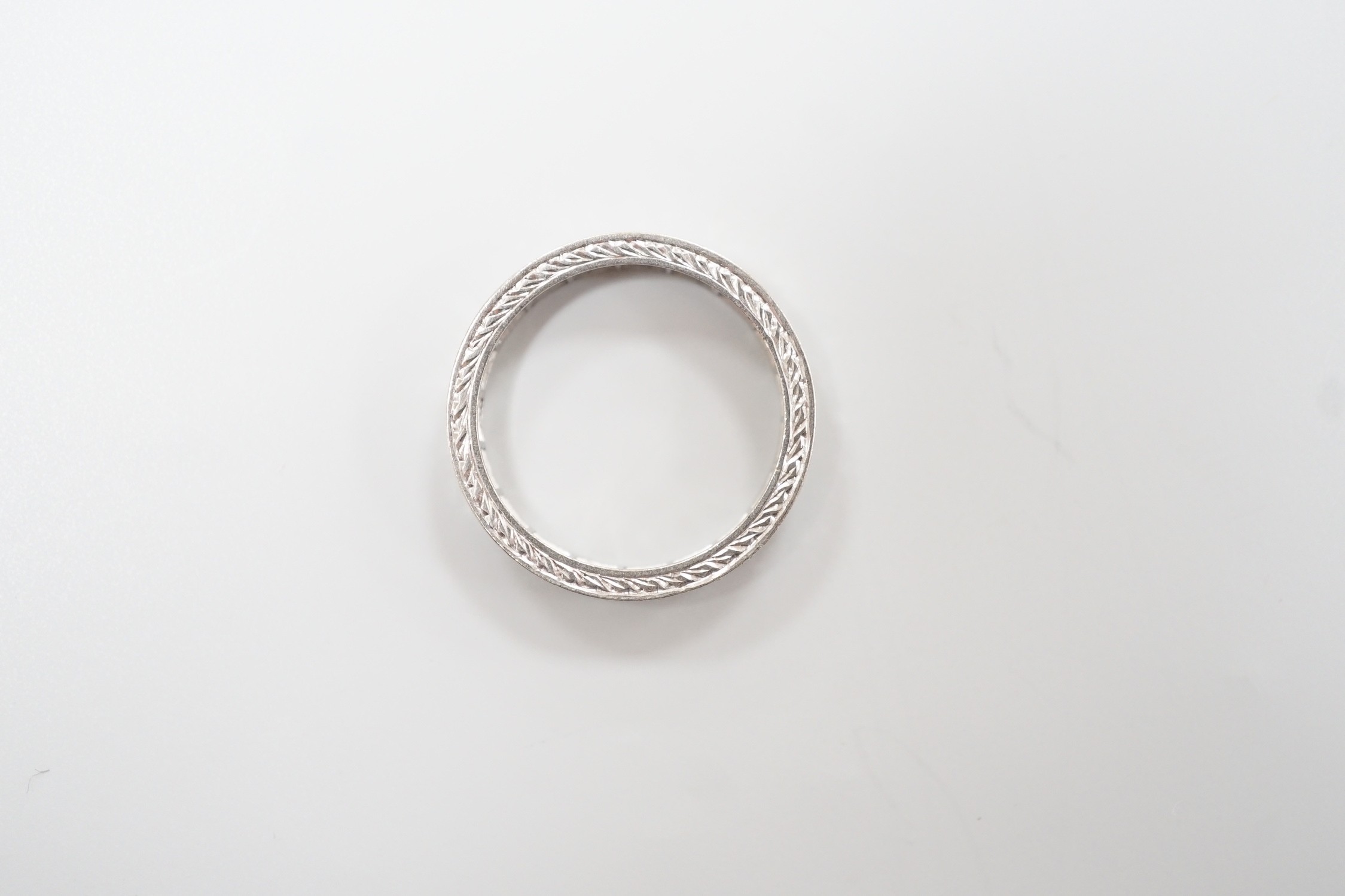 A white metal, stamped plat and diamond chip set full eternity ring, size K, gross weight 3.7 grams.